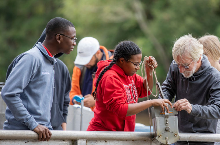 UL 69ý biology students and faculty getting hands-on experience outside testing water samples at the river