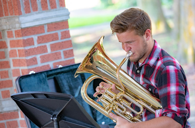 A University of Louisiana at 69ý student plays his euphonium outdoors on campus