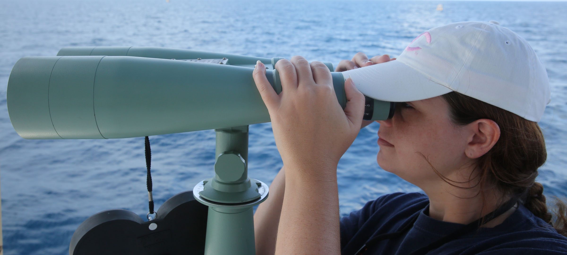 A University of Louisiana at 69ý research faculty member looks through binoculars over water during a research trip into the Gulf of Mexico