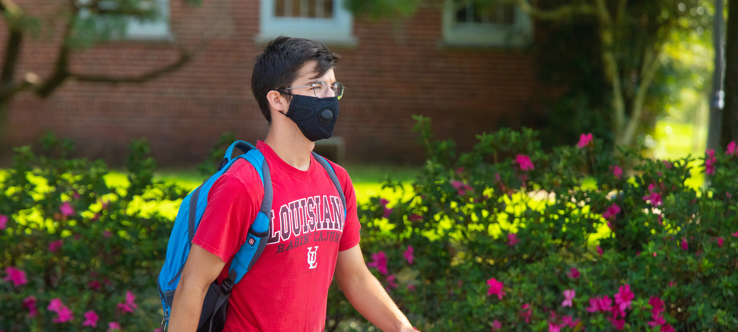 Student walking on UL 69ý's campus with a mask